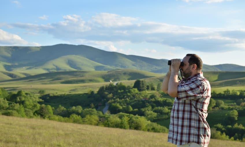 Man watching landscape through binoculars